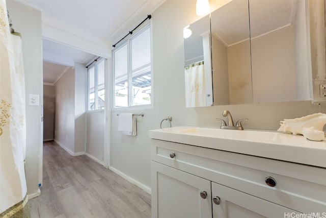 full bathroom featuring baseboards, wood finished floors, vanity, and ornamental molding