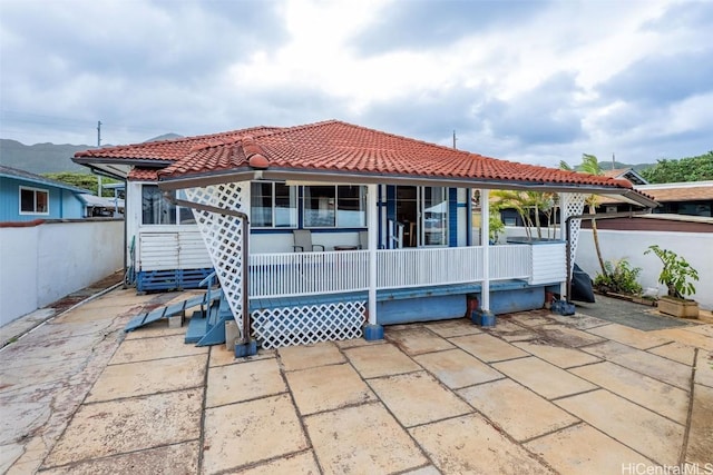 back of property with a tiled roof and fence