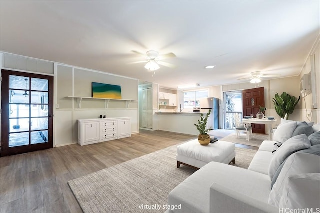 living area with plenty of natural light, light wood-type flooring, and ceiling fan