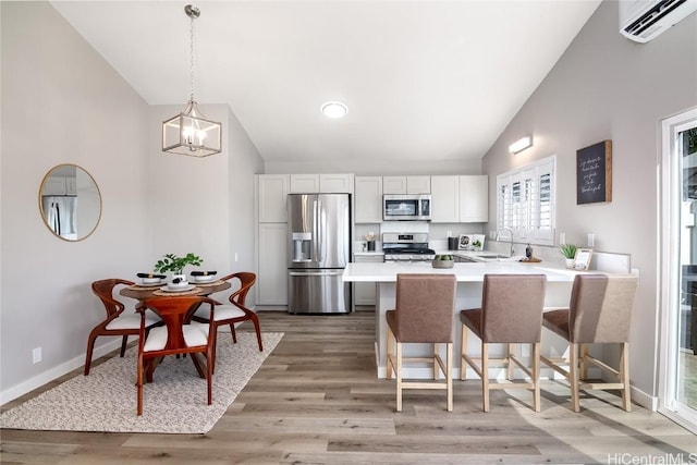 kitchen featuring white cabinetry, appliances with stainless steel finishes, a wall mounted air conditioner, and a breakfast bar area