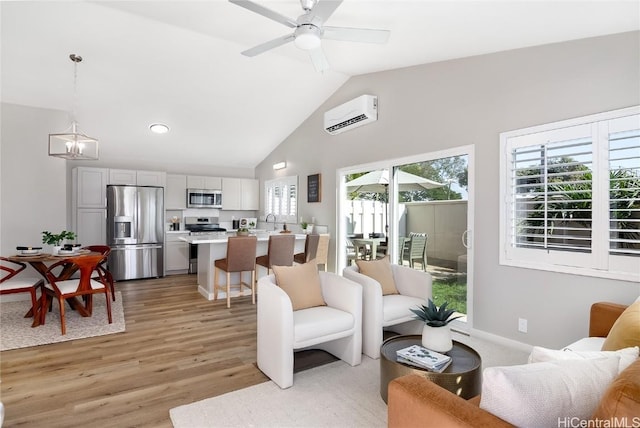 living room featuring an AC wall unit, ceiling fan with notable chandelier, high vaulted ceiling, sink, and light hardwood / wood-style floors