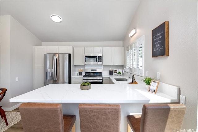 kitchen featuring white cabinetry, stainless steel appliances, sink, and a breakfast bar area