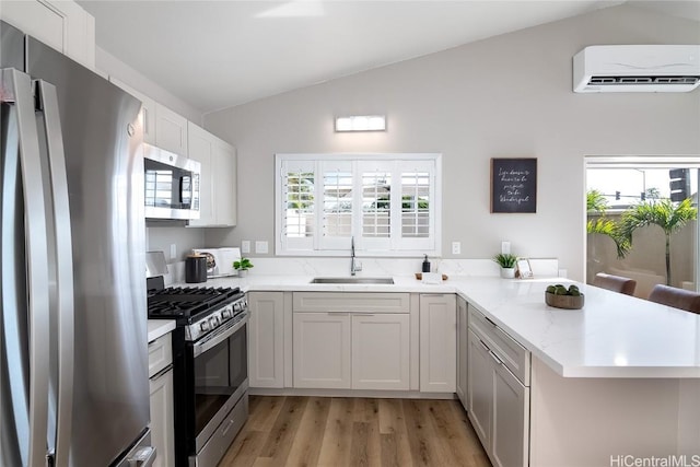 kitchen with sink, white cabinetry, a wall mounted AC, appliances with stainless steel finishes, and kitchen peninsula