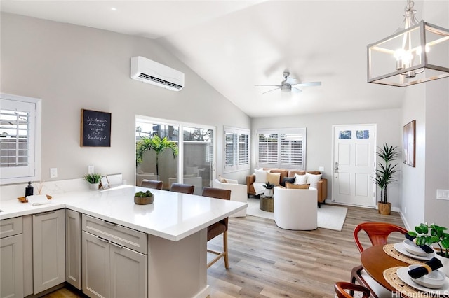 kitchen featuring a breakfast bar, gray cabinetry, a wall mounted air conditioner, kitchen peninsula, and pendant lighting