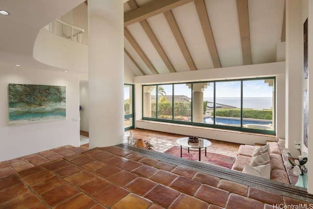 unfurnished living room with beamed ceiling, plenty of natural light, high vaulted ceiling, and a water view