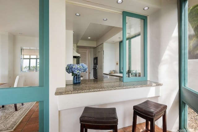 kitchen featuring black microwave, oven, and kitchen peninsula