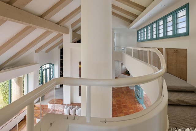 stairs featuring beam ceiling and high vaulted ceiling