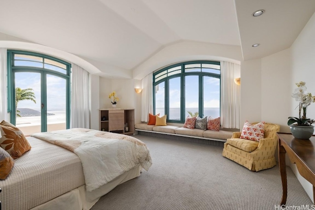 bedroom with multiple windows, a water view, lofted ceiling, and carpet