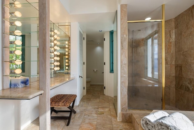 bathroom featuring a shower with door and toilet