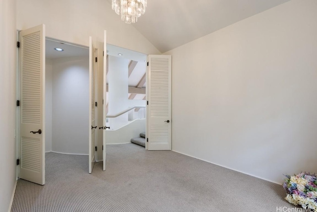 unfurnished bedroom with an inviting chandelier, lofted ceiling, and light carpet