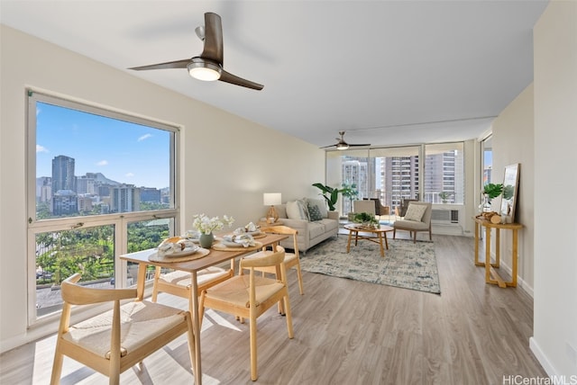 dining space with light wood finished floors, ceiling fan, a view of city, and baseboards