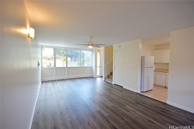 unfurnished living room with ceiling fan, stairway, wood finished floors, and baseboards