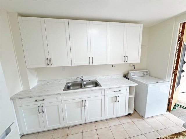 clothes washing area with sink, washer / clothes dryer, cabinets, and light tile patterned floors