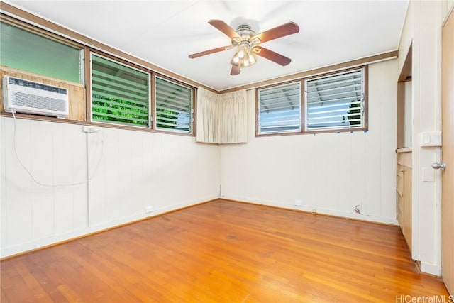 empty room with hardwood / wood-style floors, plenty of natural light, a wall mounted AC, and ceiling fan