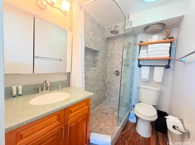 bathroom with vanity, tiled shower, hardwood / wood-style floors, and toilet