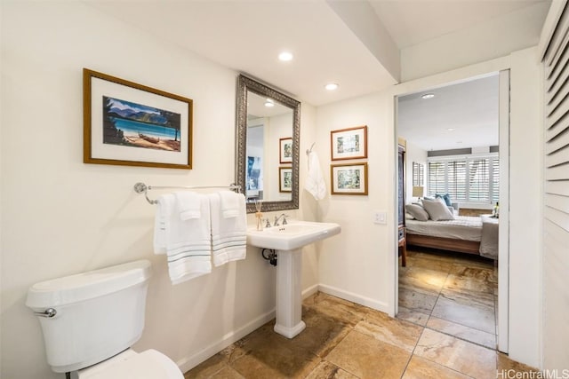 bathroom with ensuite bathroom, toilet, recessed lighting, a sink, and baseboards