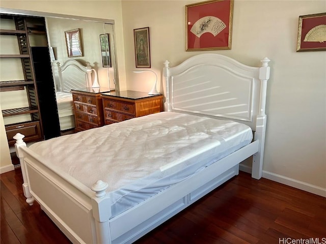 bedroom with dark hardwood / wood-style floors and a closet