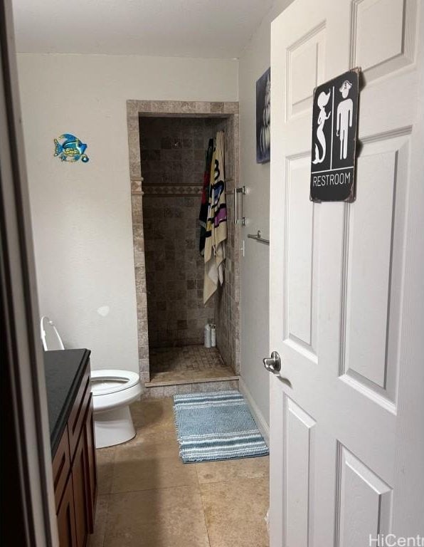 bathroom featuring a tile shower, vanity, tile patterned floors, and toilet