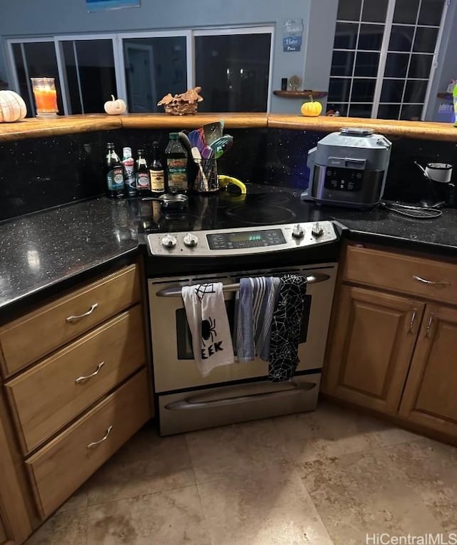 kitchen with electric stove, dark stone countertops, and light tile patterned flooring