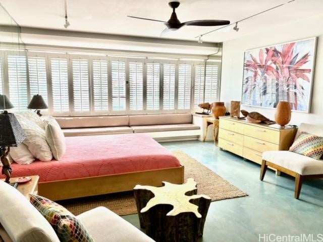 bedroom featuring ceiling fan, finished concrete flooring, and track lighting