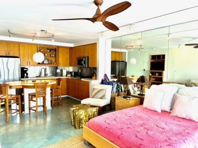 bedroom with finished concrete floors, a sink, freestanding refrigerator, and track lighting