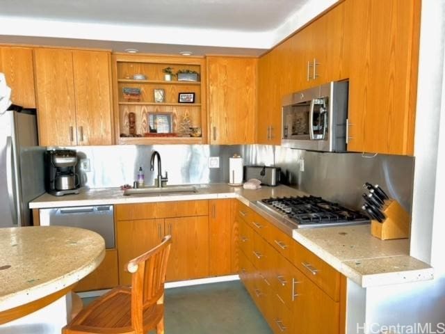 kitchen featuring brown cabinets, open shelves, tasteful backsplash, appliances with stainless steel finishes, and a sink