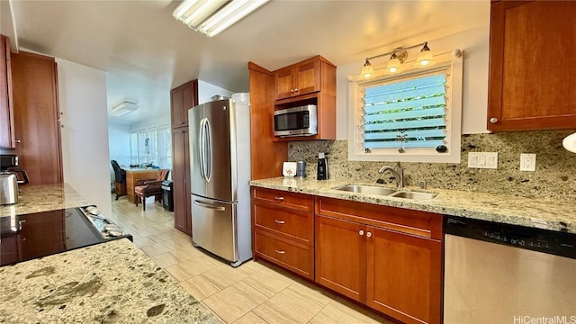 kitchen with stainless steel appliances, tasteful backsplash, light stone countertops, and sink