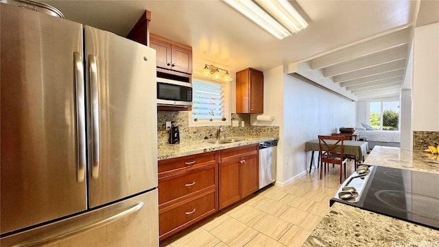 kitchen with sink, light stone counters, plenty of natural light, stainless steel appliances, and decorative backsplash