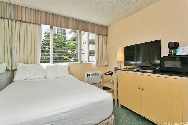 bedroom with dark carpet, a textured ceiling, and an AC wall unit