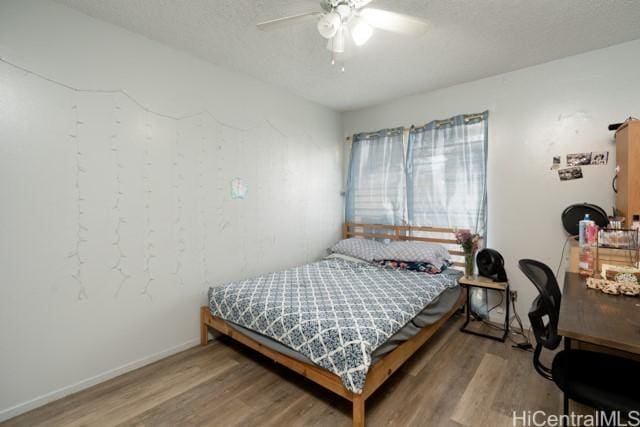 bedroom with ceiling fan, hardwood / wood-style floors, and a textured ceiling