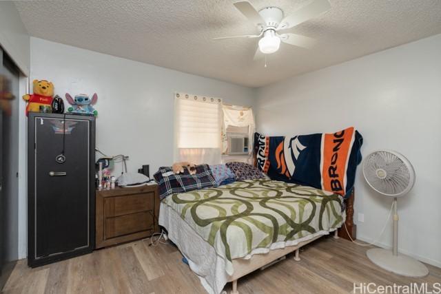 bedroom with hardwood / wood-style flooring, ceiling fan, and a textured ceiling