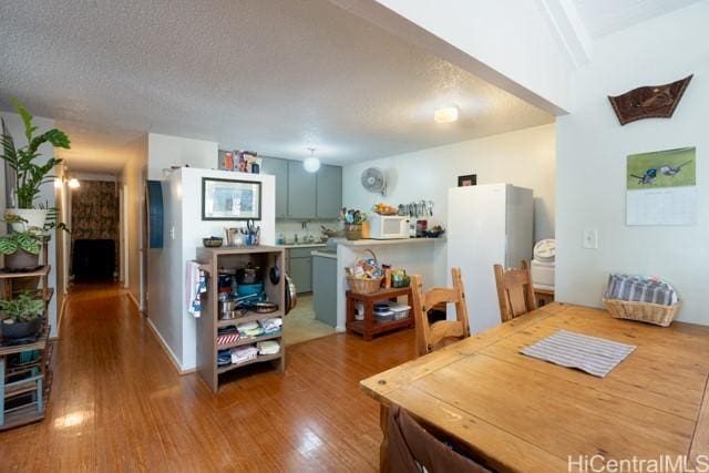 dining space with wood-type flooring and a textured ceiling