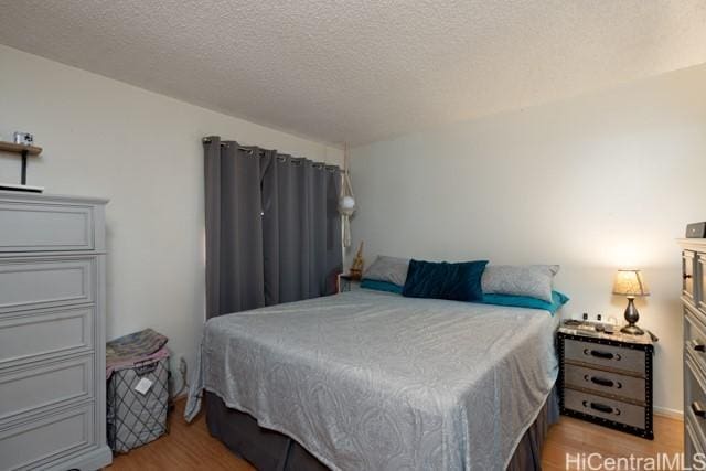 bedroom with a textured ceiling and light wood-type flooring