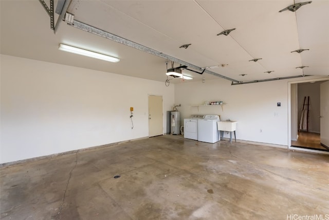 garage featuring washing machine and clothes dryer, a garage door opener, sink, and water heater