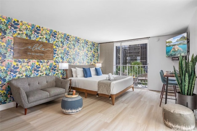 bedroom featuring a wall of windows, access to exterior, and light hardwood / wood-style floors