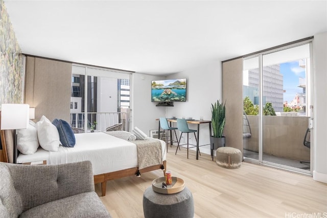 bedroom featuring light hardwood / wood-style flooring, access to outside, and a wall of windows