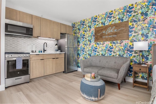 kitchen featuring sink, appliances with stainless steel finishes, tasteful backsplash, light hardwood / wood-style floors, and light brown cabinetry