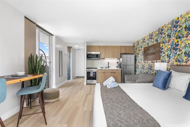 bedroom with stainless steel refrigerator, sink, and light hardwood / wood-style floors