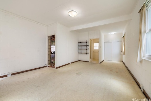 carpeted spare room featuring concrete block wall