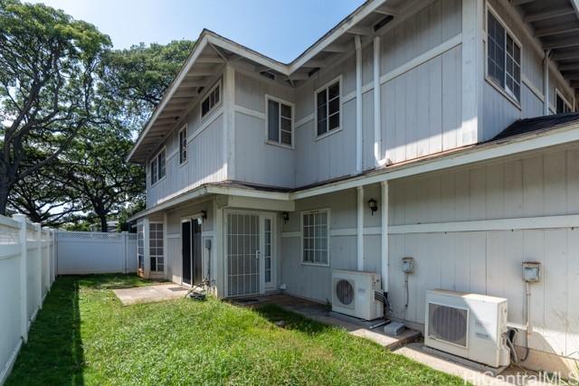 rear view of house with ac unit and a lawn