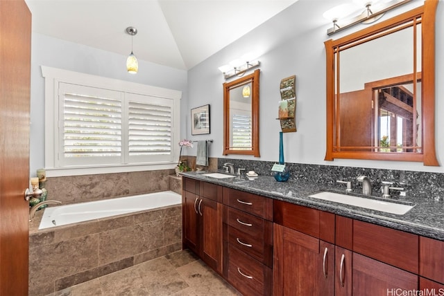 bathroom with lofted ceiling, tiled tub, vanity, and a wealth of natural light