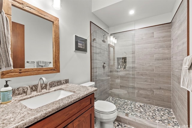 bathroom with vanity, toilet, and a tile shower