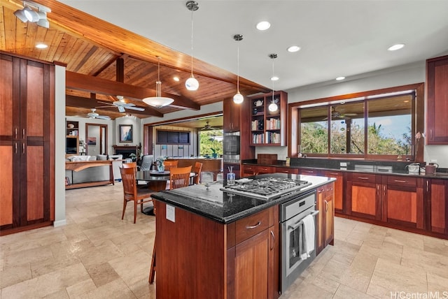 kitchen with decorative light fixtures, plenty of natural light, appliances with stainless steel finishes, a kitchen island, and dark stone counters