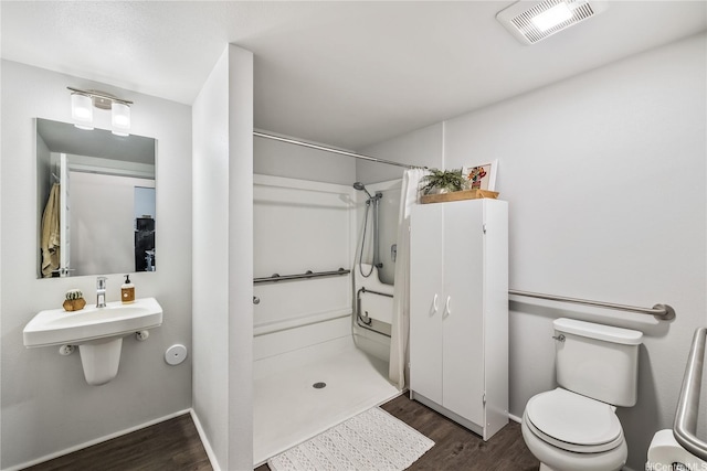 bathroom with visible vents, toilet, a stall shower, and wood finished floors