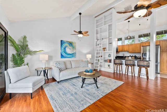 living area with visible vents, ceiling fan, beam ceiling, wood finished floors, and high vaulted ceiling