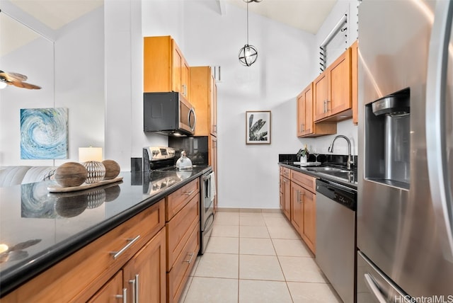 kitchen featuring pendant lighting, light tile patterned floors, appliances with stainless steel finishes, brown cabinetry, and a sink