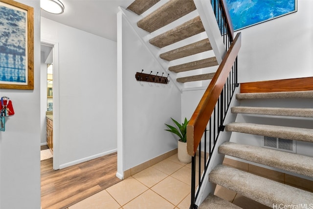 stairs with tile patterned flooring, visible vents, and baseboards