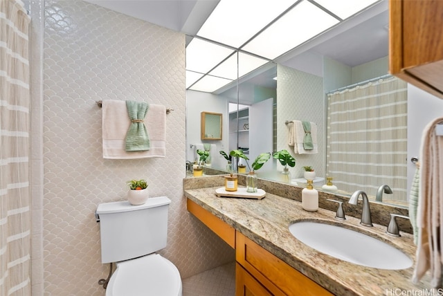 bathroom with toilet, curtained shower, a skylight, and vanity