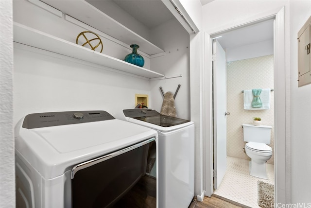 clothes washing area with washing machine and clothes dryer, laundry area, and tile walls