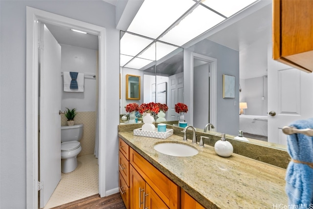 bathroom featuring toilet, tile walls, a skylight, wainscoting, and vanity